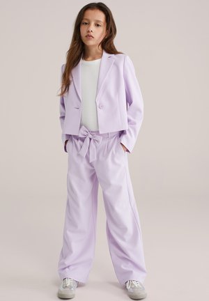 Lilla pasteldžemper ühekordse nupuga, kombineeritud laiade jalgadega pükstega, millel on lipsuvöö. Allpool valge keha jälgiv top.