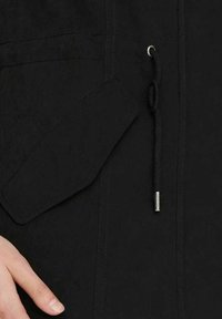 Černá bunda s texturovanou tkaninou, která má náprsní kapsu a stahovací šňůrku. Kovové detaily dodávají designu výraznost.