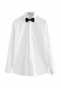 Camicia bianca con cravatta a farfalla nera, dotata di colletto classico, maniche lunghe e tessuto strutturato. Chiusura con bottoni sul davanti.