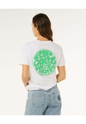 Mujer con cabello largo y castaño que lleva una camiseta blanca con un gran logo circular verde "Rip Curl Wet & Sour" y pantalones vaqueros azul claro.