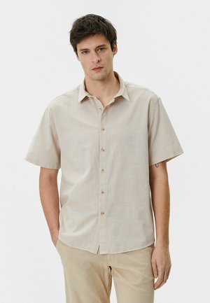 Beige kortærmet skjorte med knaplukning fortil, let tekstureret stof og klassisk krave; har uigennemsigtige knapper og en afslappet pasform.