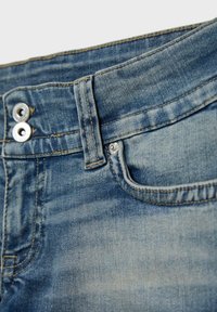 Close-up of blue denim jeans waistband with double metal buttons, belt loop, and front pocket details.