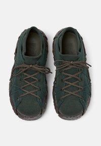Green knit sneakers with a textured finish and dark brown rubber sole. Features crisscross laces and reinforced toe caps.