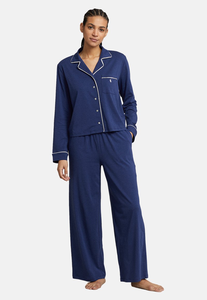 Set de pijama bleumarin cu mâneci lungi și pantaloni largi, cu detalii cu dantelă albă și buzunar pe piept, confecționat dintr-un material moale.