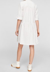 Robe à rayures claires avec des manches courtes retroussées, détail de empiècement à l'avant, jupe froncée, fabriquée dans un tissu doux, assortie à des chaussures blanches à la cheville.