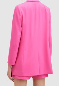 Rosa skräddarsydd kavaj med långa ärmar, en enda slits och strukturerade axlar, kombinerad med matchande shorts. Slät tyg med en rik textur.