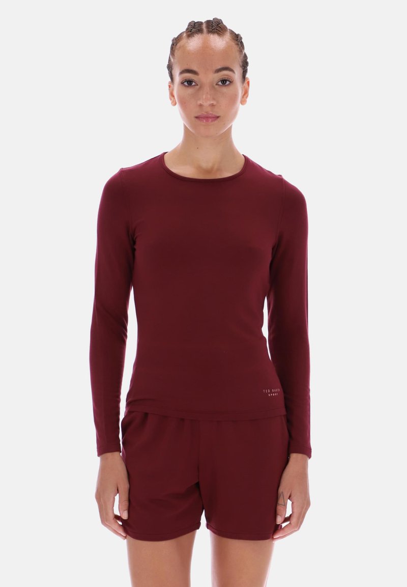 Cămașă bordó cu mânecă lungă, guler rotund și croială ajustată, asociată cu pantaloni scurți asortați. Textură netedă cu un branding subtil pe margine.