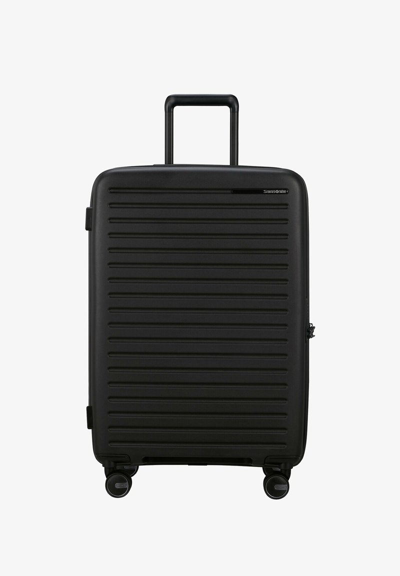 Schwarzer Rollkoffer mit gerippter Außenfläche, ausziehbarem Griff und vier schwenkbaren Rädern. Verfügt über ein Reißverschlussfach und Logodetails.