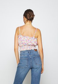 Blommig croppad topp med volangkant, vit bas och små blommor i flera färger; kombinerad med högmidjade blå jeans i denim med bakfickor.