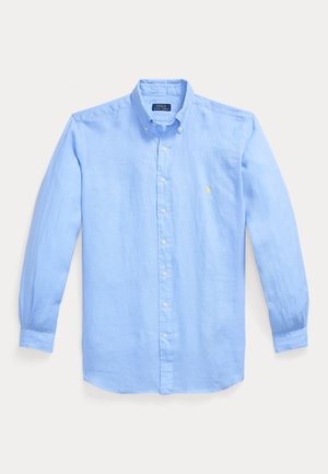 Svetlo modra dolgo rokavna srajca z gumbi, ovratnik na gumbe in majhno rumeno vezeno logotipom na levi prsni strani.