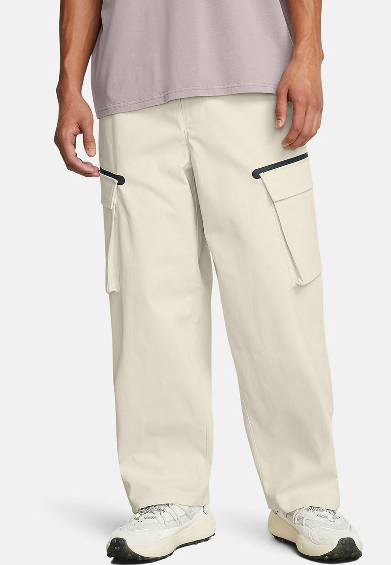 Beiga cargo-byxor med svarta detaljer, med sidofickor och en lös passform. Matchat med en ljuslila skjorta och neutrala sneakers.