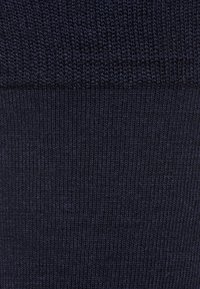 Marineblauw ribgebreide stof met een gladde textuur. Het ontwerp bevat verticale lijnen en een consistente kleur in het geheel. Zacht en flexibele materiaal.