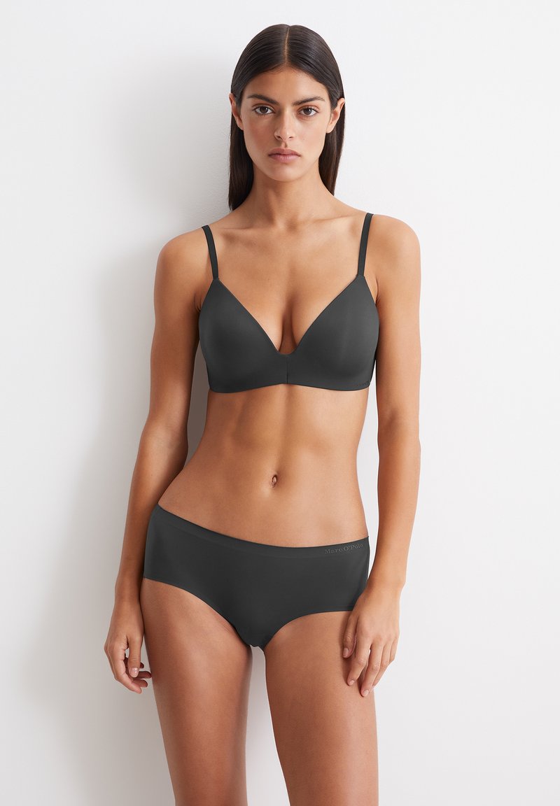 Schwarzer nahtloser BH mit dünnen Trägern und tiefem Ausschnitt, kombiniert mit passenden hochgeschnittenen Slips. Glatte Textur, minimalistisches Design.
