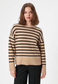 Maglione beige a righe con righe orizzontali nere, maniche lunghe, collo e polsini a costine e vestibilità rilassata.