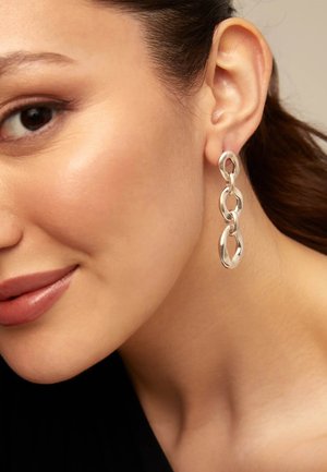 Boucles d'oreilles en maillons d'argent composées de formes ovales allongées et interconnectées avec une finition polie, mettant en valeur des surfaces réfléchissantes et un design sans faille.