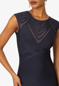 Marineblaues, tailliertes Kleid mit strukturiertem plissiertem Oberteil und durchsichtigen Einsätzen. Akzentuiert mit Trägern und einer glatten Textur. Klassiker, elegantes Design.