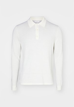 Valge pikade varrukatega polo-särk pehmest materjalist, krae peal, kolme nööbiga kinnitusega ja soonikuga mansettidega. Sile tekstuur, minimaalne disain.