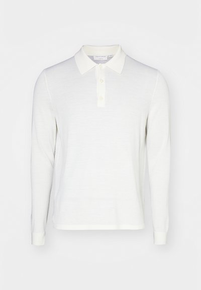 Fehér, hosszú ujjú polo ing, puha anyagból, galléros nyakkal, három gombos megoldással és bordázott mandzsettákkal. Simaság, minimális dizájn.
