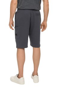 Shorts cargo marine en tissu doux, dotés de poches latérales, d'une poche arrière et d'une coupe décontractée. Associés à des baskets blanches.