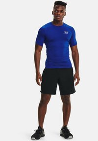 Blauw sportshirt met korte mouwen, gemaakt van rekbaar materiaal, gecombineerd met zwarte shorts. Heeft een nauwsluitend ontwerp en een logo op de borst.