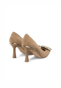 Beige suede high-heeled pumps with pointed toes, decorative crystal accents at the front, and a slim, structured heel.