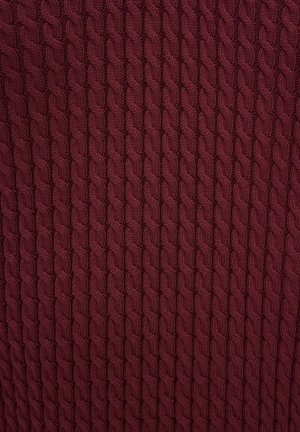 Dyb bordeauxfarvet strikket stof med et gentaget tekstureret kabelmønster, der skaber lodrette flettede rækker.