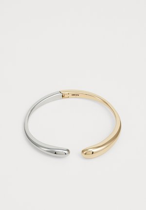 Silver and gold two-tone cuff bracelet, featuring smooth, rounded ends and a minimalist design with a polished finish. Brand engraved inside.