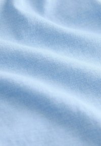 Light blue cotton fabric with a smooth texture and subtle ribbing pattern, showcasing gentle folds and a soft appearance.