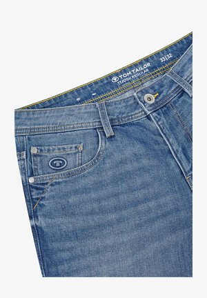 Blauwe denim jeans met een regular fit, stevige tailleband met gele stiksel, en een klein voorvak met een merklogo.