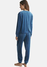 Blauw, zacht velours loungewear set met een langmouwen top en bijpassende broek. Beide items hebben een relaxed fit en geribde manchetten.