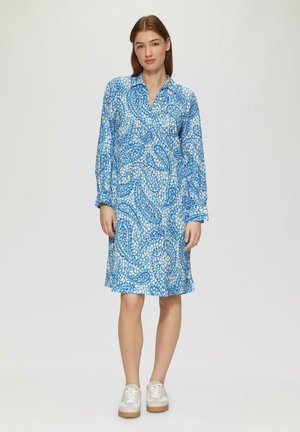 Blaue Paisleymuster-Kleid-Shirt mit langen Ärmeln und Kragen. Aus leichtem Stoff gefertigt. Kombiniert mit weißen Turnschuhen.