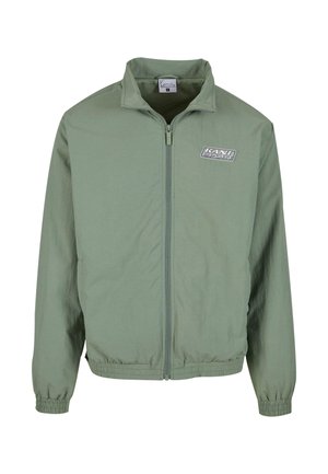 Light green zip-up jacket with a stand collar, elastic cuffs, and waistband. Features a logo patch on the chest in gray and black.
