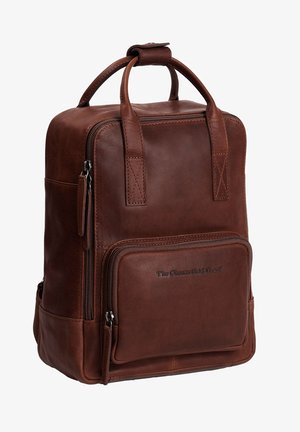 Sac à dos en cuir marron au design compact, avec double poignées, une poche zippée à l'avant et un logo embossé sur le bas à l'avant.