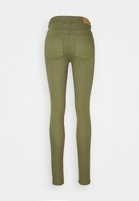 Jean skinny vert olive avec une texture lisse, une taille haute et deux poches arrière. Comprend un petit patch en cuir sur la ceinture.
