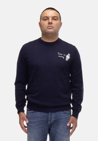 Maglione lavorato a maglia blu navy con maniche lunghe, scollatura tonda, con ricamo bianco di un orologio e il testo "Il tempo è denaro" sul petto.