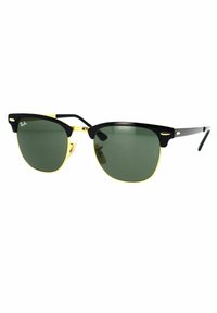 Occhiali da sole Ray-Ban con montatura nera, lenti verdi e dettagli dorati. Design classico con una forma audace e sopracciglia ben definite.