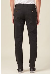 Schwarze Hosen mit geradem Schnitt, ausgestattet mit Gesäßtaschen mit goldfarbenen Knöpfen und einem glatten, strukturierten Stoff.