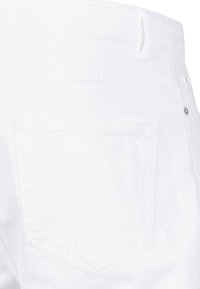 Jeans blancos con un bolsillo trasero, hechos de denim. Las características incluyen un corte recto, presillas para el cinturón y un acento de botón de metal. Textura suave.
