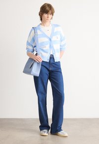 Blue and white striped cardigan, blue tote bag, white t-shirt, denim jeans, silver sneakers, casual fit, soft textures, relaxed design.