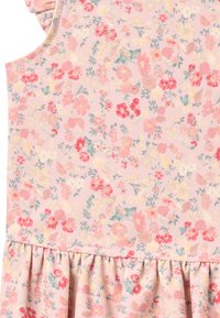 Tissu à motif floral en rose pastel avec des fleurs rouges et jaunes ; présente une taille froncée et un design sans manches. Texture douce en coton.