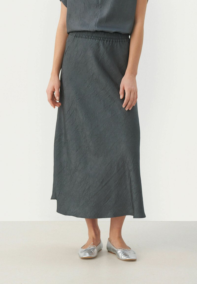 Grijze midi-rok van textuurstof, met een elastische tailleband. Gekoeld met glanzende zilveren platte schoenen.