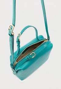Τσάντα ώμου από δέρμα σε πράσινο-μπλε απόχρωση με δομημένο σχήμα, επάνω φερμουάρ και ρυθμιζόμενο λουράκι. Χρυσά μεταλλικά στοιχεία προσθέτουν κομψότητα στο σχέδιο.