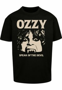 Sort bomulds t-shirt med et stort, trykt grafisk motiv af et ansigt med hugtænder og vildt hår. Teksten ovenfor og nedenfor lyder "OZZY" og "SPEAK OF THE DEVIL."