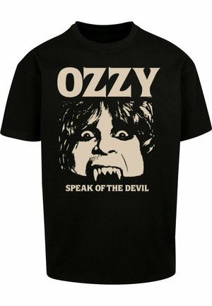 Černé bavlněné tričko se velkým, sítotiskem vytištěným grafickým motivem obličeje se tesáky a divokými vlasy. Text nahoře a dole zní "OZZY" a "MLUV O ĎÁBLU."