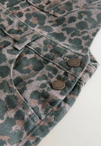 Green denim fabric with a leopard print pattern in dark green and pale pink. Features two metal buttons and visible stitching details.