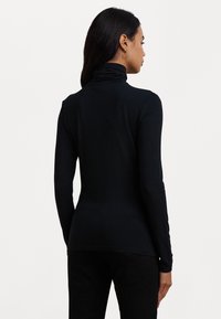 Zwarte langharige turtleneck top van een zachte, rekbare stof met een slanke pasvorm en subtiele plooidetail bij de hals.
