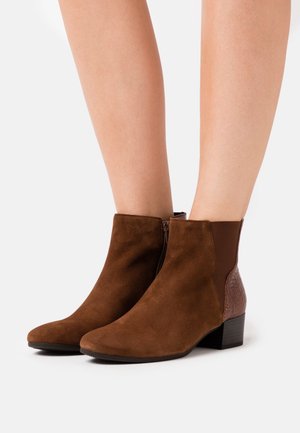 Bottines en suède marron avec un panneau texturé et des accents élastiques sur les côtés. Équipées d'un talon bas et d'un design à bout pointu.