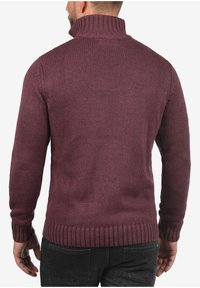 Maglione a coste color bordeaux con collo alto, polsini e orlo a coste. Presenta un tessuto texturizzato con un design aderente.