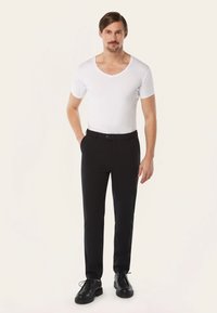 Witte T-shirt met korte mouwen en V-hals, met een slim fit, gecombineerd met zwarte, op maat gemaakte broek en zwarte veterschoenen, tegen een neutrale achtergrond.