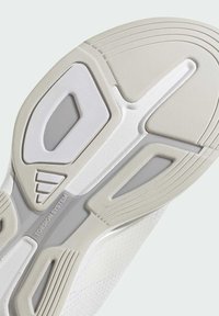 Schuhsohle mit einem strukturierten weißen Oberteil, geschwungenem Design, breiten Rillen und einem grauen Akzent, der "TORSION SYSTEM" in der Nähe eines hohlen Abschnitts anzeigt.
